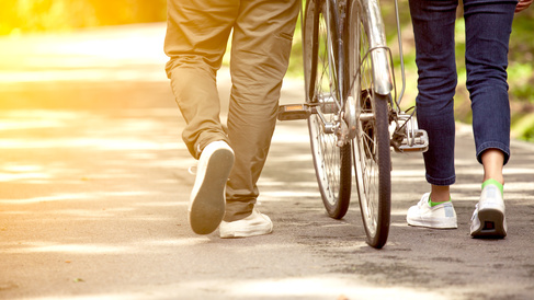 People walking through park with a bike