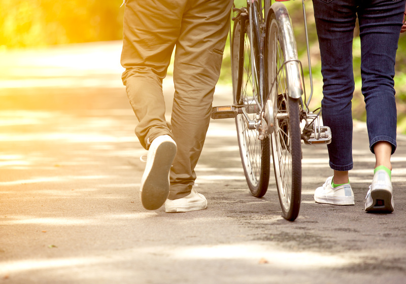 People walking through park with a bike